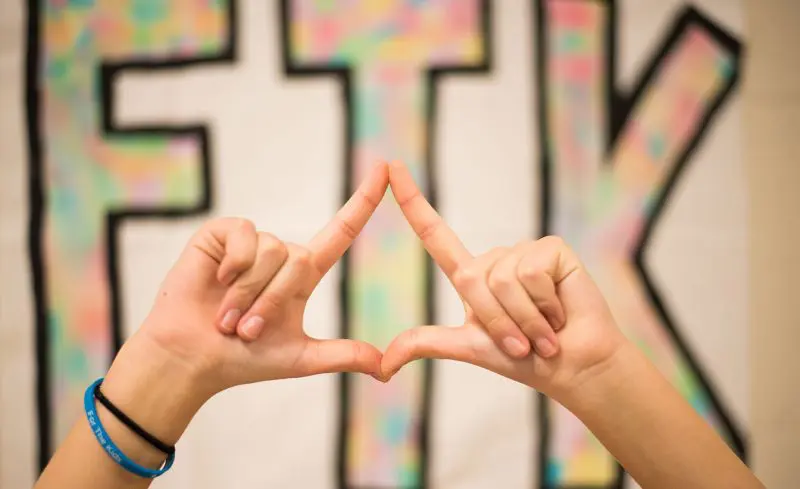 A person forming a diamond with their fingers, representing Four Diamonds, with FTK (For the Kids) in the background (Four Diamonds)
